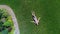 Woman dreaming lying on grass, aerial view, rotating drone fly above garden lady