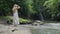 Woman with a dress enjoys leisurely walk by the watercourse, admiring waterfall