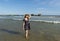 Woman in the dress and hat standing in the ocean at the Weligama beach