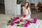 Woman in dress sitting on her knees, near flowers of peonies