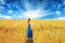 Woman in dress standing walking through open wheat field