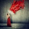 Woman in dress using an umbrella as shelter against red drops paint falling down