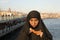 Woman dressed black headscarf, chador eating simit, istanbul, turkey