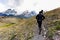 woman dressed in dark clothing walking along pathway with Torres del Paine mountain range in the back