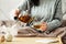 Woman dressed in knitted sweater pours hot tea from glass teapot into mug while sitting in bed. Morning breakfast in cozy home