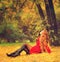 Woman dressed in red coat relaxing in autumn park.