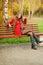 Woman dressed in red coat sitting in autumn park.