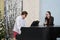 Woman,dressed up in fancy black dress with champagne glass and man in shorts and shirt playing piano at New Year party celebration