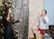 Woman,dressed up in fancy black dress with champagne glass surprised by man in shorts, shirt, socks showing off by Christmas tree