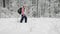 Woman dressed in warm sports clothes with a backpack actively walking on a footpath in the forest holding in her hands a