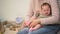 Woman dressing little cute infant girl in pink socks, natural clothing materials