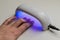 Woman dries gel nail polish under ultraviolet lamp