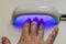 Woman dries gel nail polish under ultraviolet lamp