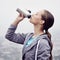 Woman, drink and water bottle for fitness, detox and wellness on cloudy day in France with mockup. Thirsty female person