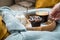 Woman drinking coffee with blueberry muffin, sugar and milk on wooden tray and comfy sofa with blue wool knit blanket and yellow