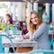 Woman drinking coffee and writing notes in cafe