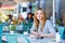 Woman drinking coffee and writing notes in cafe