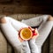 Woman drinking coffee. Young female manicured hands holding cup of hot coffee with fresh foam on floor background.