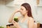 Woman drinking disgusting green smoothie, closing nose, bad smell and taste