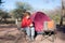 Woman drinking hot coffee mug while relaxing in camping site. Tent, chairs and camping gears. Outdoor activities in summer. Advent