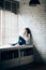 Woman drinking hot coffee sitting on window sill at home