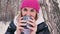 Woman is drinking hot tea or coffee from a cup in a snowy forest, wants to warm herself in the winter outdoors with a