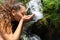 Woman drinking raw water from waterfall