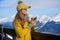 Woman drinking warm tea in the rustick wooden terrace on mountain, alpine view, snow on hills