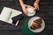 Woman drinks cappuccino in a cafe. Croissant, notapad, smartphone and bank card on a wooden table