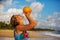 A woman drinks coconut at the seashore at sunset