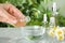 Woman dripping essential oil into bowl on table,