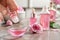 Woman dripping rose essential oil into bowl on table, closeup