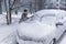 Woman driver cleans windshield of her car from snow