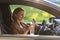 Woman driver drinks water from a refillable bottle in her car, stopped to rest