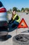 Woman driver fixing changed wheel on roadside