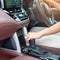 Woman driver stick shift transmission a car gear, hand controlling steering wheel during vehicle moving. Journey, trip and safety