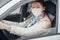 A woman driving a car puts on a medical mask during an epidemic, a taxi driver a woman in a mask, protection from the virus