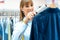 Woman in dry cleaning store is using lint roller to clean a jacket