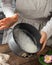 Woman dusting a greased cake baking mold with grated coconut