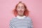 Woman with dyed pink hair doing facial expression and touching nose with tongue