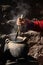 Woman dyeing wool in clay pot for weaving