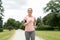 Woman with earphones and armband jogging at park