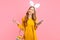 Woman in the ears of an Easter Bunny, holding a basket of Easter eggs, with a mobile phone in her hands on an pink background