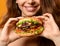 Woman eat burger sandwich with hungry mouth on yellow background