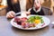 Woman eat healthy lunch in restaurant. Grilled meat steak with cranberry sauce, glazed peaches and arugula salad