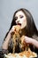 woman eat spaghetti with hands. Hungry girl have italian food meal. Beauty model with makeup and long brunette hair