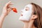 Woman eat strawberry. Young beautiful woman with facial mask and strawberry