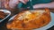 Woman eating Adjarian Khachapuri with a fork in a Georgian restaurant on a wooden table. Georgian food