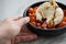 Woman eating Buffalo Burrata mozzarella cheese ball with cocktail tomatoes, olive oil and balsamic vinegar on black plate