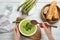 Woman eating delicious asparagus soup at wooden table, top view